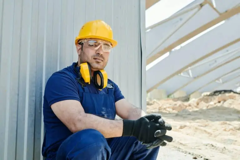 Construction trades worker leaning against a building